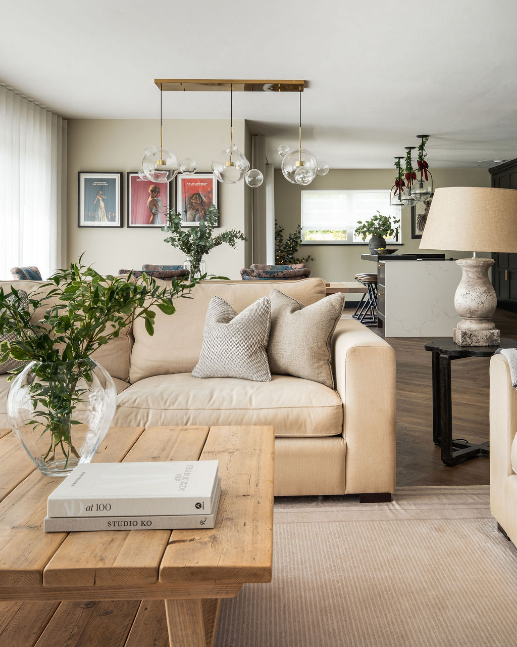 Contemporary open plan living room in a modern barn conversion. Deep neutral sofas are set on a large rug with natural wood coffee table and dark wood side tables.